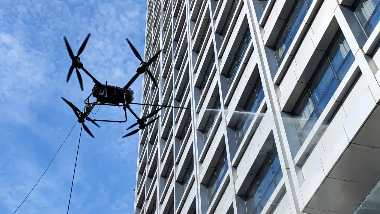 Drone spraying water onto a building facade